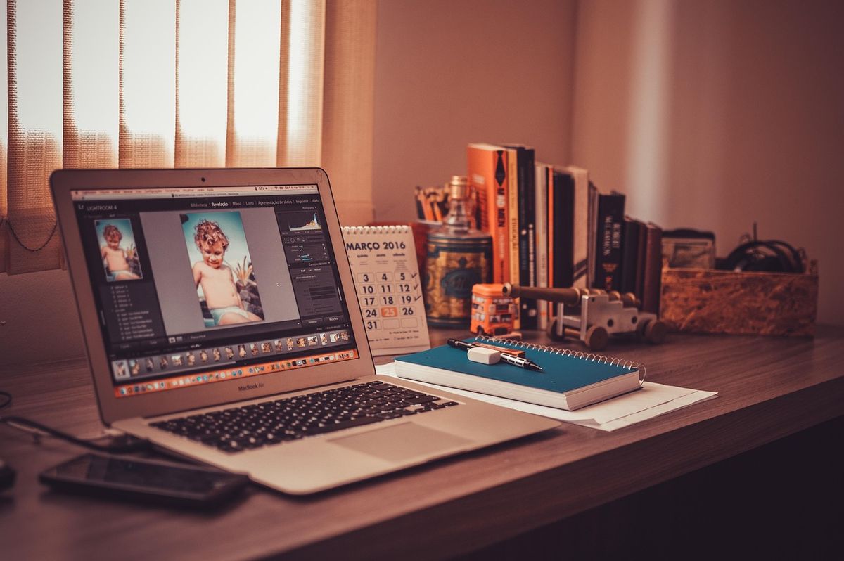 Laptop, notebook and books on a wooden home-office desk