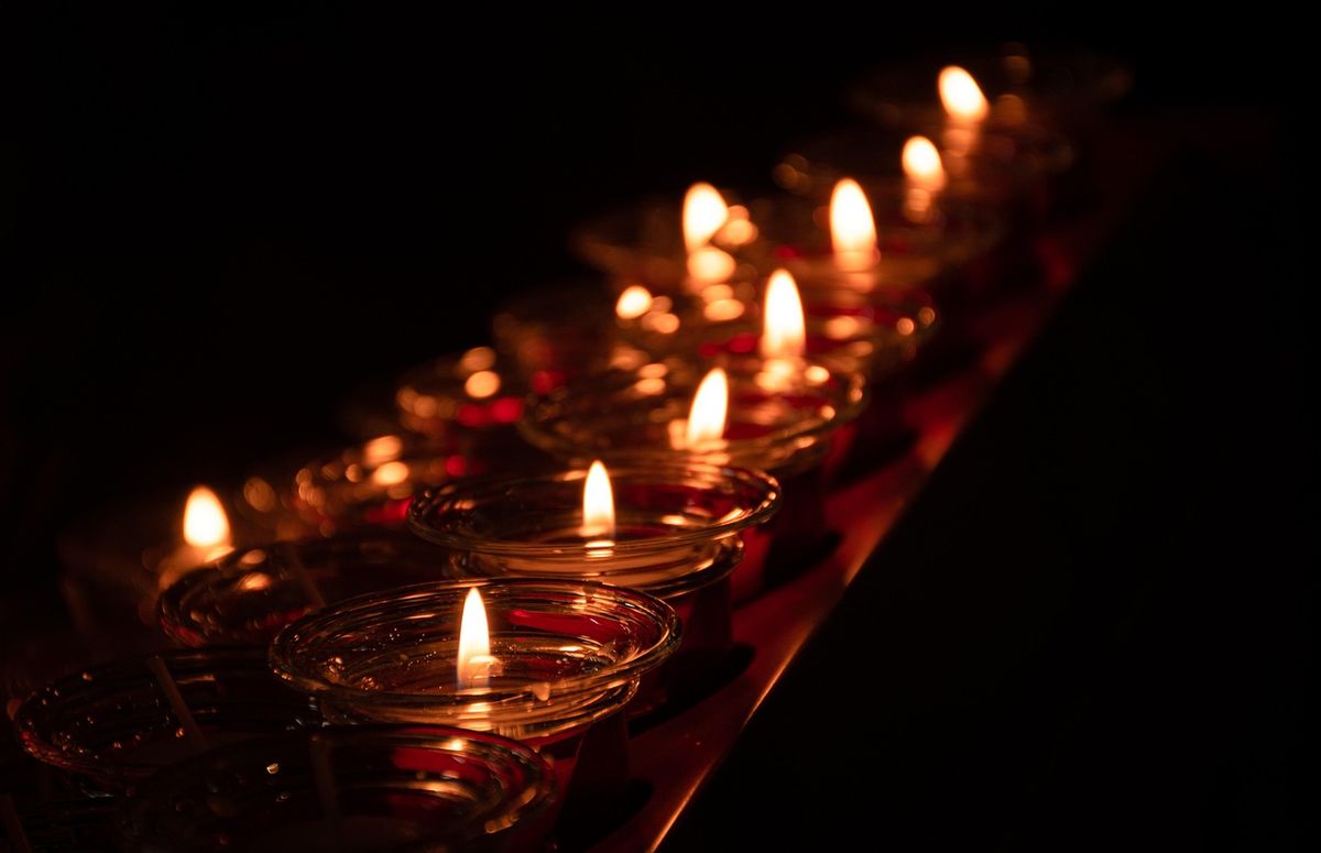 Row of lit tea-light candles glowing in the dark