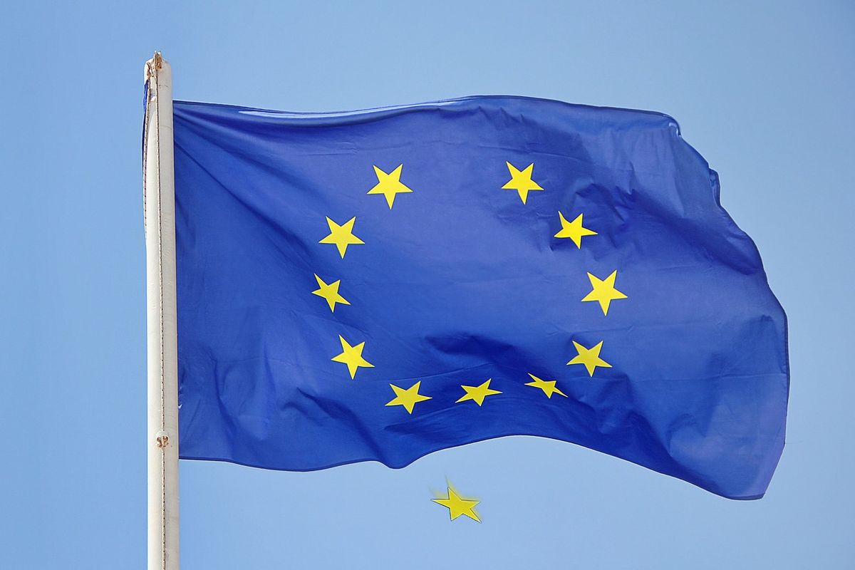EU flag on a flagpole with one star falling away, symbolising Brexit